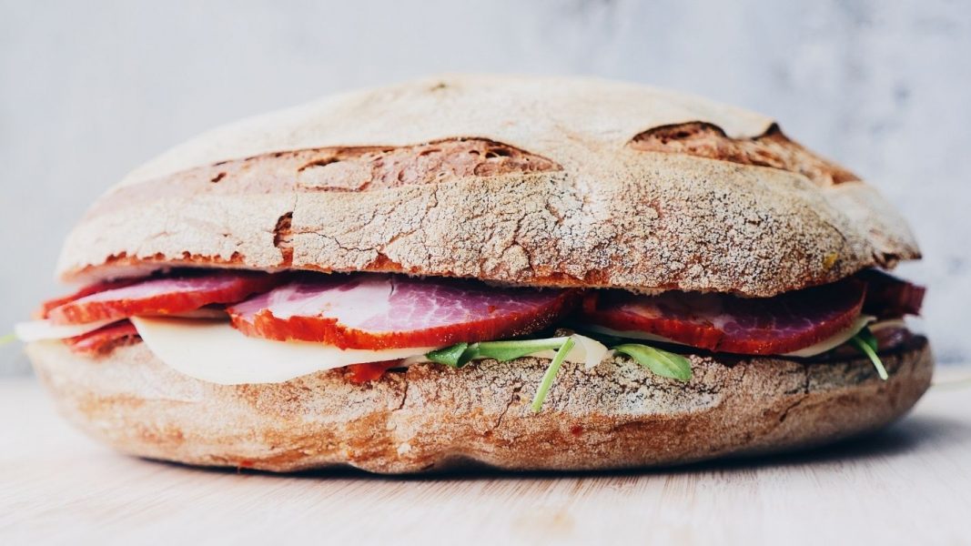 Sandwich mit Weißbrot, Schinken, Käse und Rucola. Ein Symbol für die Entwicklung der Ernährung.